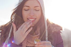 A woman rubs cream on her lips