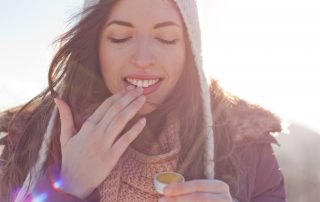 A woman rubs cream on her lips