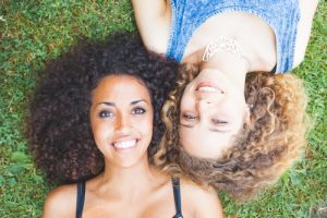 Two girls lay by each other with curly hair.