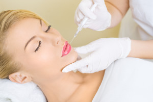 Young woman receiving botox injection in lips