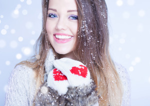 Winter face close up of young woman covered with snowflakes