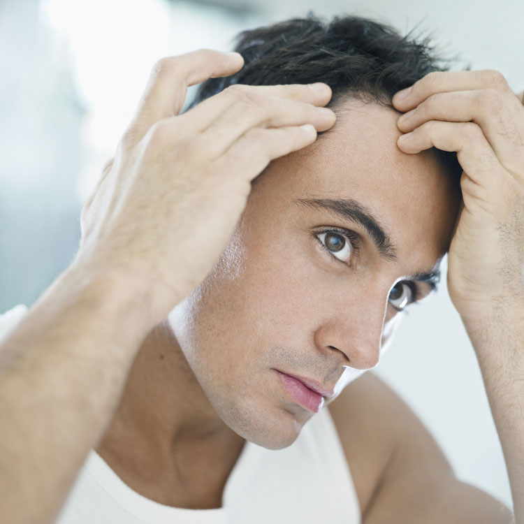 Man worrying about hair loss, looking in mirror