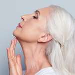 white haired woman looking up and touching her chin