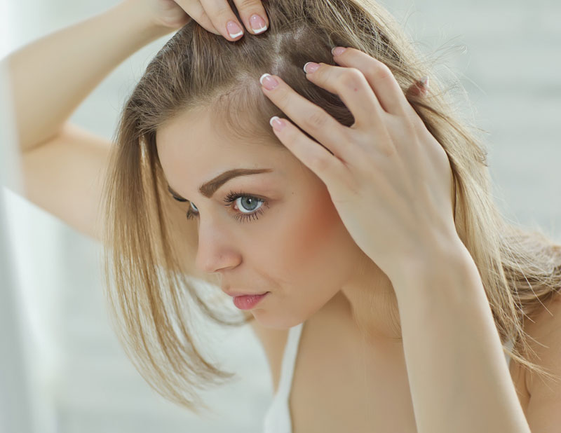 Woman looking at her hair, worrying about hair loss