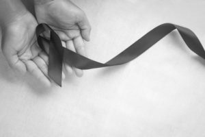 Hand holding Black ribbon on white fabric background with copy s