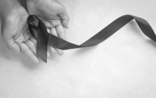 Hand holding Black ribbon on white fabric background with copy s