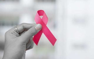 female hand holding breast cancer ribbon