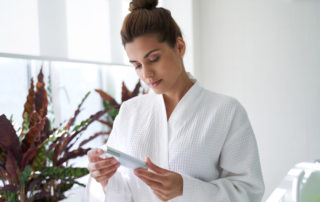 woman looking at skin cream in bath robe