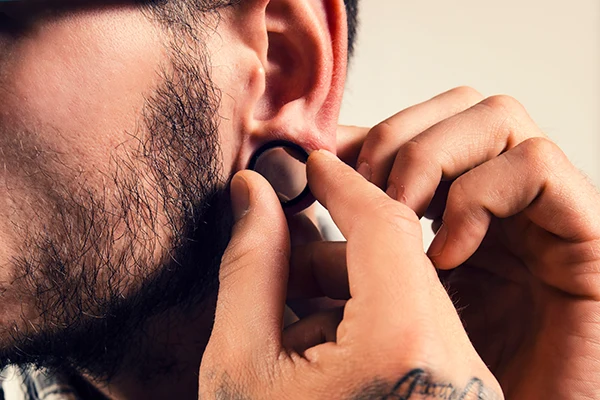 A man adjusts a gauged earring piercing