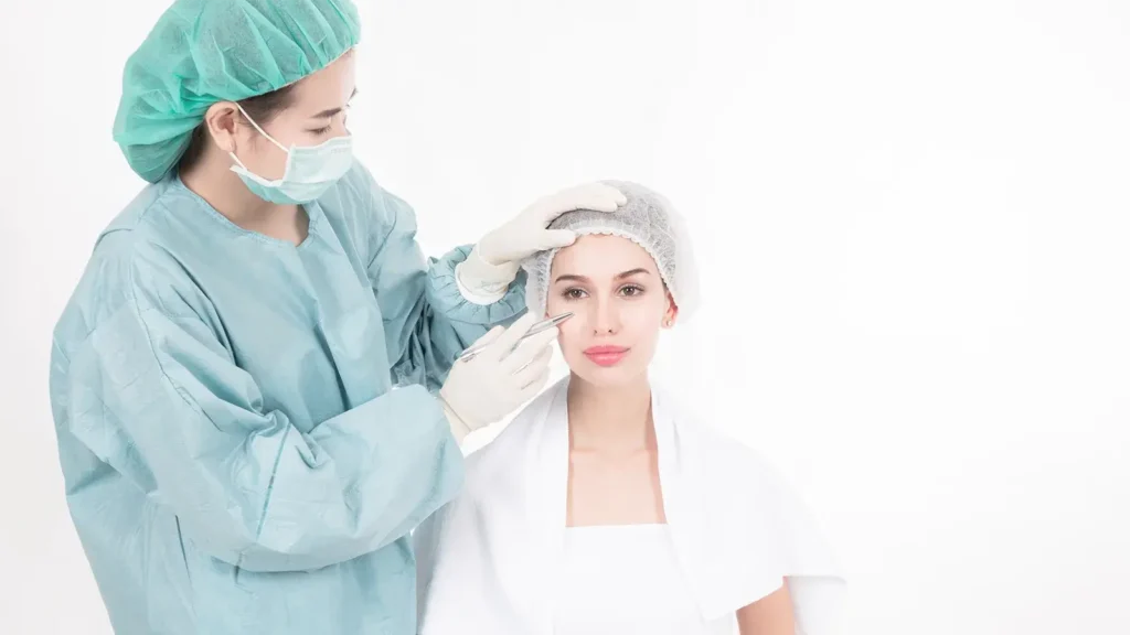 A surgeon in green consulting with a patient in white regarding rhinoplasty techniques